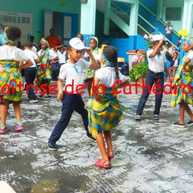Enfants qui dansent en habits martiquainais traditionnels dans la cour de récréation