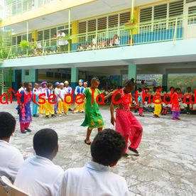 Enfants qui dansent dans l'enceinte de l'école avec des tenues très colorées